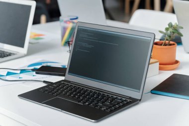 Bilgisayarın yakın plan görüntüsü ve kodlar bilişim bürosundaki programcının masasında.