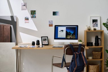 Modern grafik tasarımcısının yatay görüntüsü. Stüdyoda bilgisayar ve profesyonel fotoğraflar asılı.