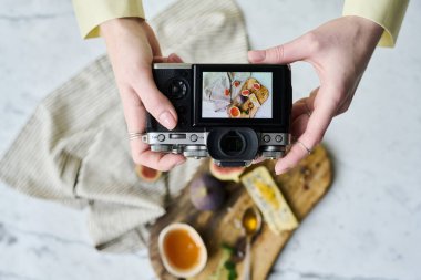 Kamerayla fotoğraf çeken profesyonel fotoğrafçının yüksek açılı görüntüsü, egzotik meyve ve peynirin hayatını fotoğraflıyor.