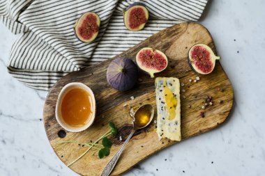 Ahşap tepside yüksek açılı yaşam manzarası ballı egzotik meyveler ve peynir