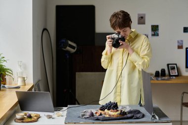 Genç bir kadın fotoğraf stüdyosundaki işi sırasında taze meyve fotoğrafları çekmek için profesyonel fotoğraf makinesi kullanıyor.