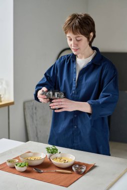 Genç profesyonel fotoğrafçı fotoğraf makinesiyle yemek masasında fotoğraf çekiyor.