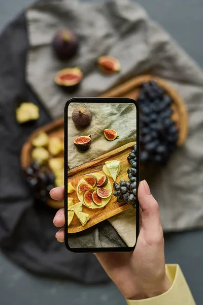 stock image High angle view of young woman photographing exotic fruits on tray using her smartphone with perfect camera