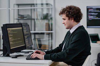 Bilgi işlem ofisinde çalışırken bilgisayardaki program için kod yazan genç bir bilişim uzmanı.