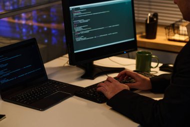 Akşam geç saatlere kadar ofiste çalışırken bilgisayarında kodlar olan bir bilgisayar programı geliştiriyor.