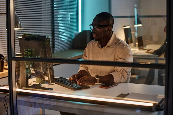 アフリカ系アメリカ人のビジネスマンは 暗いオフィスでの仕事中にコンピュータに集中して — ストック写真