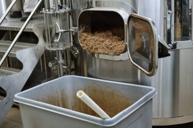 Fabrikadaki geri dönüşüm sırasında atık dolu boruların çöp kutusuna döküldüğü yakın çekim.