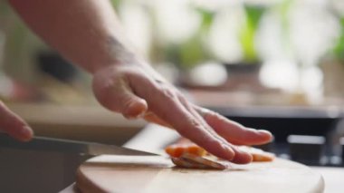 Mutfak masasında yemek hazırlarken, erkek şefin pişmiş karidesi ikiye böldüğü yakın çekim.