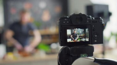 Profesyonel kameranın seçici odak noktasını kapat. Yemek blogcusunun mutfakta yemek pişirirken videosunu çek ve yemek tarifini söyle.
