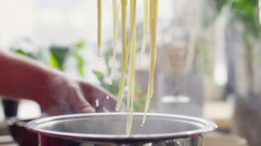 Şefin ellerinin, süzmek için taze pişmiş makarnayı kevgire koyuşuna yakından bakın.