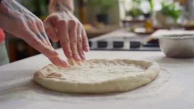 Pizza pişirirken mutfak masasında hamuru yassılaştıran erkek elleri yakın çekim