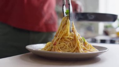 Mutfak dilleri tabakta sıcak spagetti servis ederken yakın çekim.