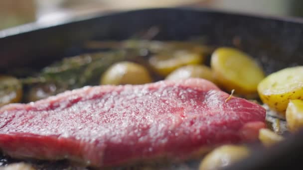 ビーフステーキやジャガイモがフライパンで調理されている様子を間近で見る — ストック動画