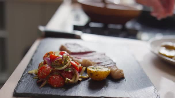 사진을 감자를 토마토 샐러드와 스테이크와 보드에 스타일리스트의 가까이 찍는다 — 비디오
