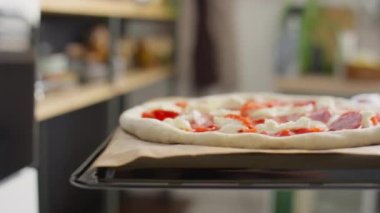 Bir adamın fırını açtığı ve pizzayı içine koyduğu yakın çekim.