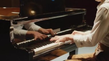 Sahnede konser salonunda piyano çalan erkek piyanistin kesikli yay çekimi.