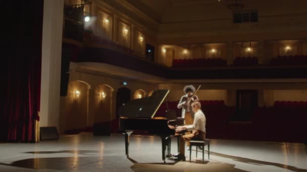 两名没有观众的职业音乐家在音乐厅一起演奏小提琴和大钢琴的宽弧形镜头 — 图库视频影像