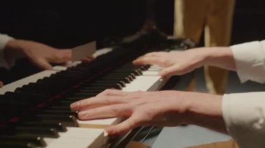 Profesyonel piyanistin sahnede keman eşliğinde klasik müzik çalarken yakın çekim.