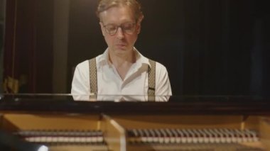 Sahnede klasik müzik çalarken kapağı açık piyano çalan virtüöz piyanist