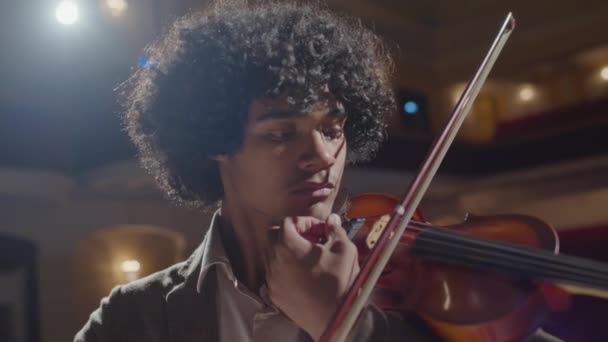 在音乐厅的独奏会上 年轻的非洲裔美国小提琴手在聚光灯下演奏小提琴的胸部镜头 — 图库视频影像