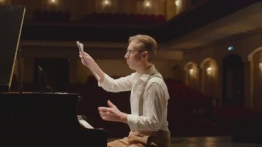 Yavaş çekimde piyanist notaları atıyor ve konser salonunda piyano çalıyor.