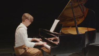 Sahnede performans sergilerken açık kapakla piyano çalan profesyonel müzisyenin orta boy çekimi.