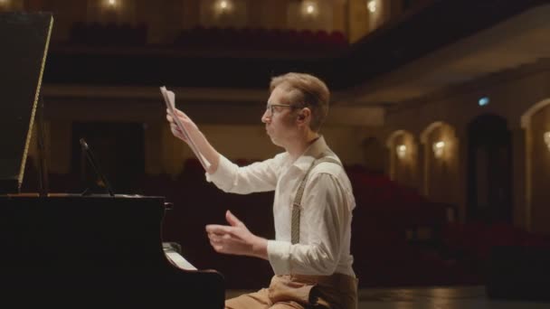 钢琴家在音乐厅的舞台上抛掷乐谱和弹奏大钢琴的弧度慢镜头 — 图库视频影像