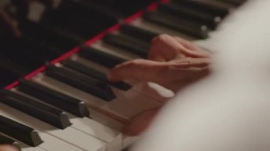 Hızlı şarkı çalarken piyano tuşlarına basan erkek müzisyenin ellerini yakın çekimde çek