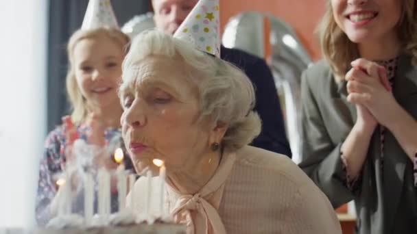 Joyous Familie Partij Hoeden Knuffelen Oudere Oma Nadat Blazen Kaarsen — Stockvideo