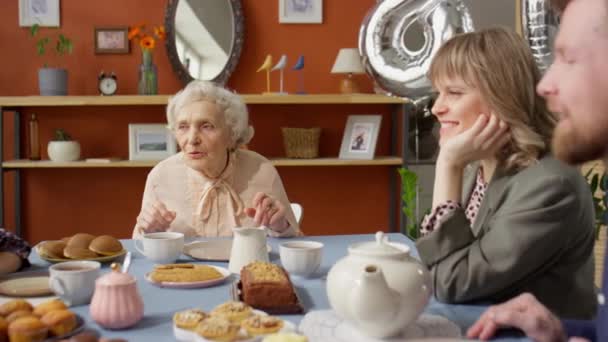 Śledzenie Zdjęcia Starszej Babci Rozmawiającej Wnukami Podczas Urodzinowej Kolacji Rodziną — Wideo stockowe