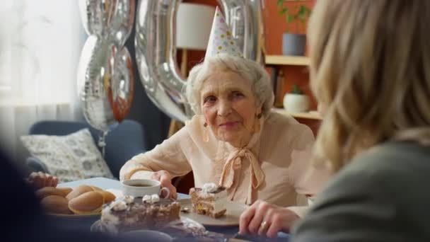 Über Die Schulter Der Glücklichen Eldelry Großmutter Mit Partyhut Sitzt — Stockvideo