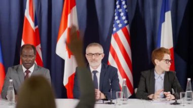 Ülkelerinin ulusal bayraklarının başında oturan ve zirve toplantısı sırasında izleyicilerin sorularını yanıtlayan dünya siyasi liderlerinin görüntüsü.
