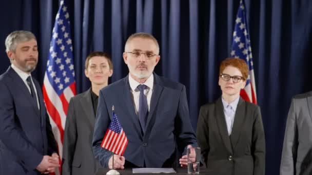 Senior Gråhårig Politiker Står Rostrum Med Amerikansk Flagga Och Ger — Stockvideo