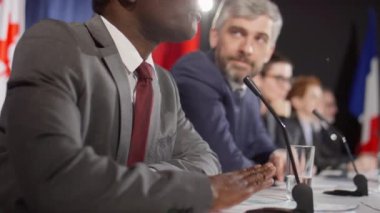 Uluslararası basın toplantısı sırasında mikrofonla konuşan Afrikalı Amerikalı politikacının görüntüsü.