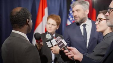 Bir grup gazeteci mikrofon tutuyor ve Afrika kökenli Amerikalı politikacıyla zirvede röportaj yapıyor.