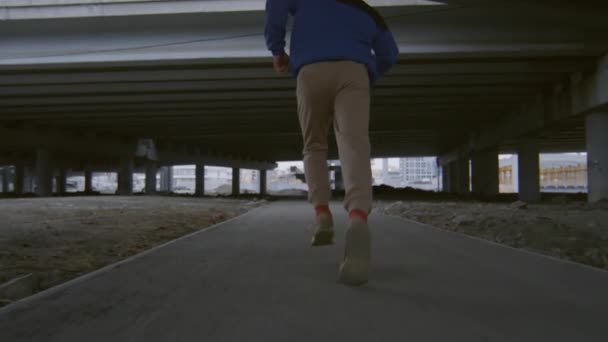 都市部の橋の下を走る若いトラクターのスローモーションショットと路上で駐車場を練習しながらサイドフリップを実行した後 — ストック動画