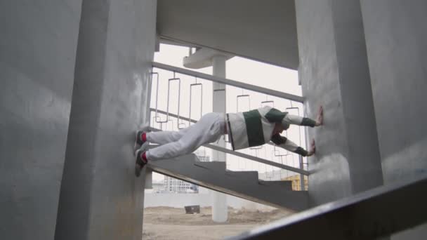 公园运动员在室外城市楼梯工作时爬过两道混凝土墙的低角度镜头 — 图库视频影像