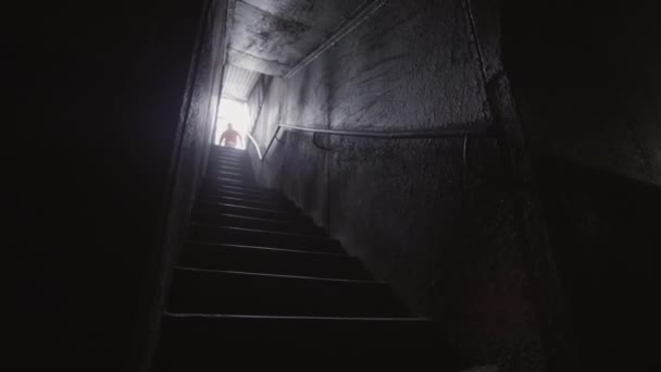 暗い廊下を通って階下に実行されているパルクール選手の低角度ショット — ストック動画