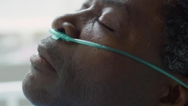 目を閉じて その後目を覚ますと ベッドの上に病院に横たわって鼻カニューレと病気のアフリカ系アメリカ人の男の上の傾きを閉じる — ストック動画