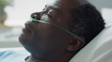Burun kanülü hasta Afro-Amerikan bir adamın hastane koğuşunda uyanması.