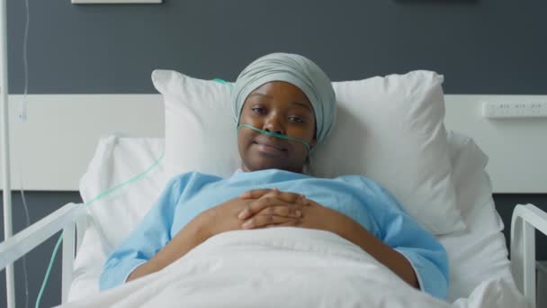 手で病院のベッドの上に横たわっています彼女の胃の上に分類し 笑顔でカメラのためにポーズ — ストック動画