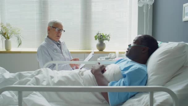 Zoom Shot Senior Caucasian Doctor Sitting Bedside Hospital Ward Speaking — Stock Video