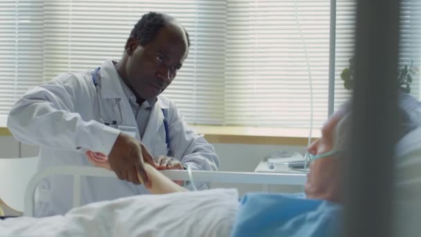 Rack Focus Shot Del Médico Afroamericano Revisando Pulso Paciente Caucásico — Vídeos de Stock