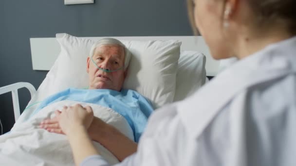 年老体衰 鼻腔发炎的男子躺在医院病房的床上 牵着他的手与女儿交谈 — 图库视频影像