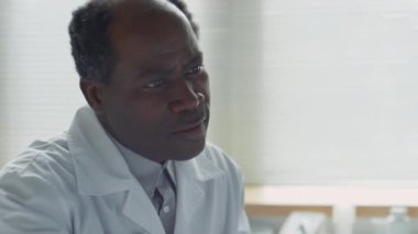 Afro-Amerikalı doktor, burun kanülü genç bir bayanın elini tutuyor ve hastanede terapi sırasında onunla konuşuyor.