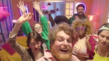 Bir grup genç arkadaş dans ediyor, gülümsüyor ve kameraya bakıyor. Y2k partisinde neon ışıkla aydınlatılıyor.