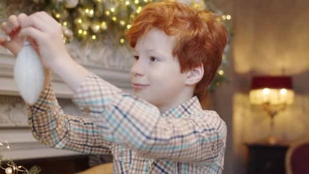 Kleine Jongen Met Gember Haar Versieren Kerstboom Gezellige Woonkamer Met — Stockvideo
