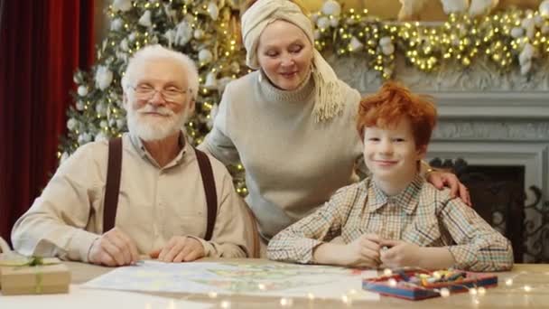 Szczęśliwi Dziadkowie Ich Wnuk Uśmiechnięci Pozujący Razem Kamery Przy Stole — Wideo stockowe