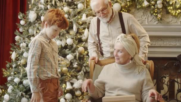 快乐的祖母从礼品盒中取出手套 抱着小孙子 和家人一起庆祝圣诞节 — 图库视频影像