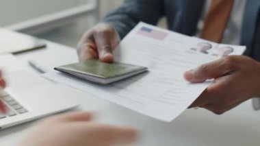 Afro-Amerikan vize memurunun evrakları ve pasaport formlarını alırken ve ABD elçiliğindeki sorgu sırasında soru sorarken yakın çekim.